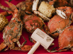 tray of maryland crabs with a mallet branded with UMBC Alumni Association
