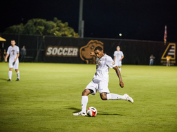 UMBC Men's Soccer player kicking a ball at night.