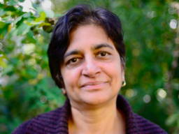 headshot of woman standing in front of a lush, green background