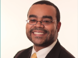 headshot of smiling man wearing glasses