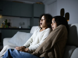 two women on a couch, screaming at a scary movie
