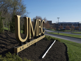 Side view photo of UMBC sign on campus.